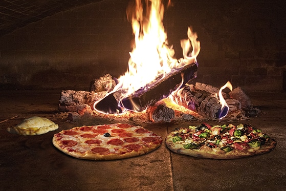 A picture of dual pizza in front of a fire